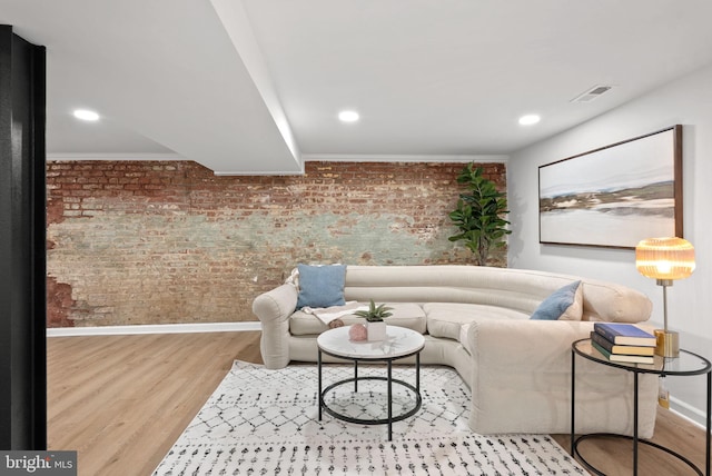 living room featuring brick wall and light wood-type flooring