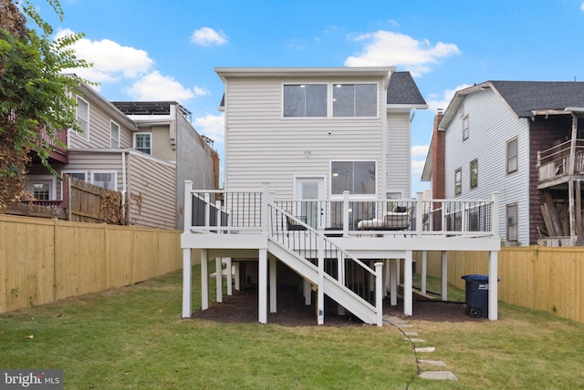 rear view of house featuring a deck and a lawn