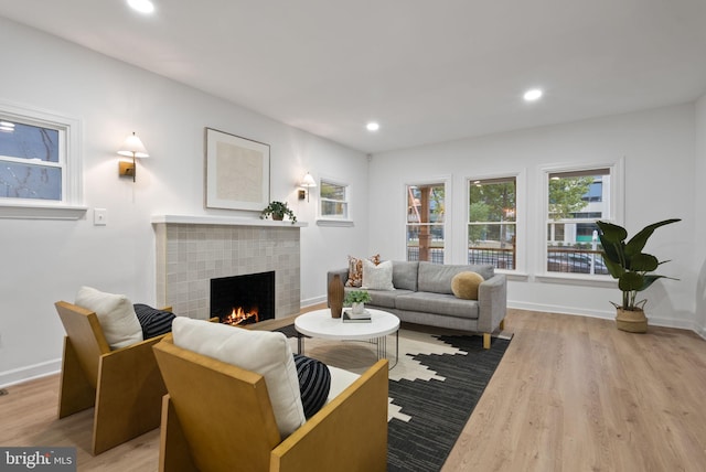 living room with a brick fireplace and light wood-type flooring