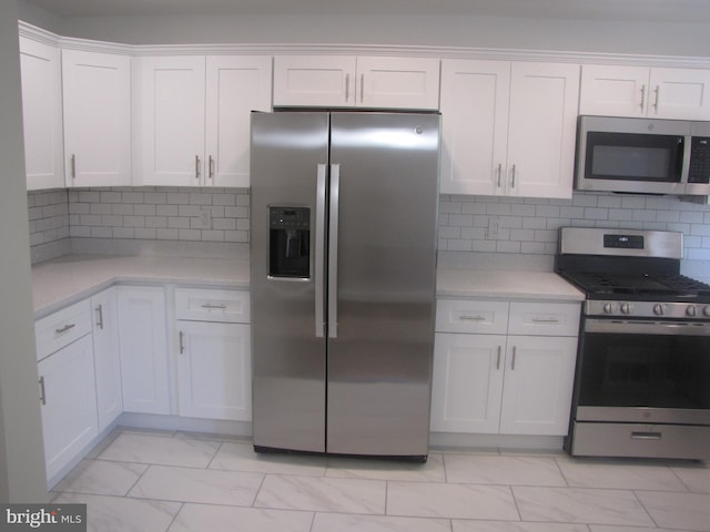 kitchen with backsplash, white cabinets, and stainless steel appliances