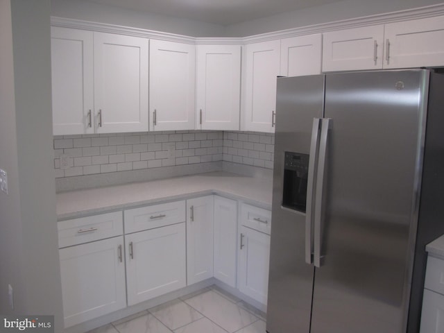 kitchen with white cabinets, decorative backsplash, and stainless steel refrigerator with ice dispenser