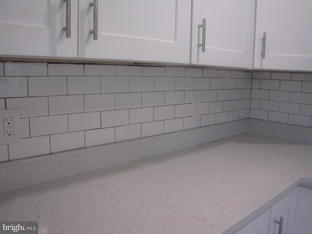 room details with decorative backsplash, white cabinetry, and light stone countertops