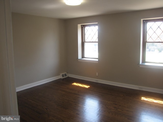 unfurnished room with a healthy amount of sunlight and dark hardwood / wood-style floors