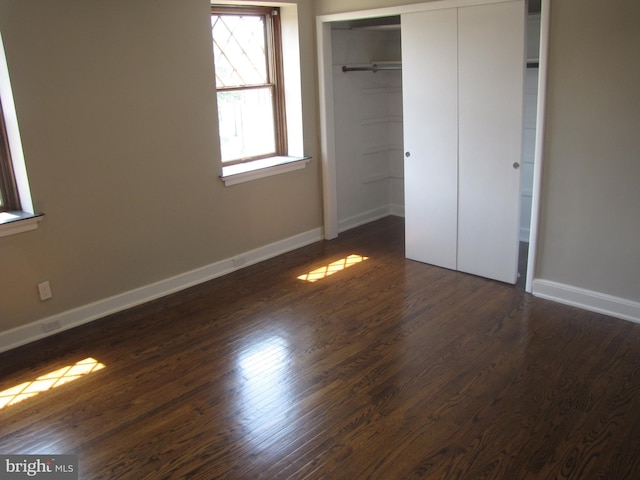 unfurnished bedroom with dark hardwood / wood-style floors and a closet