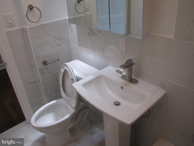 bathroom with tasteful backsplash, sink, tile walls, and toilet