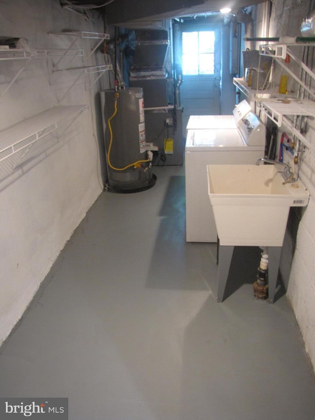 basement featuring washing machine and clothes dryer, sink, heating unit, and water heater