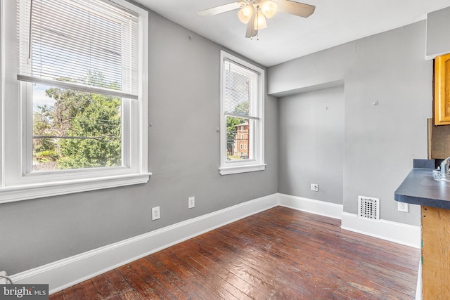 unfurnished dining area with ceiling fan, dark wood-type flooring, and a healthy amount of sunlight