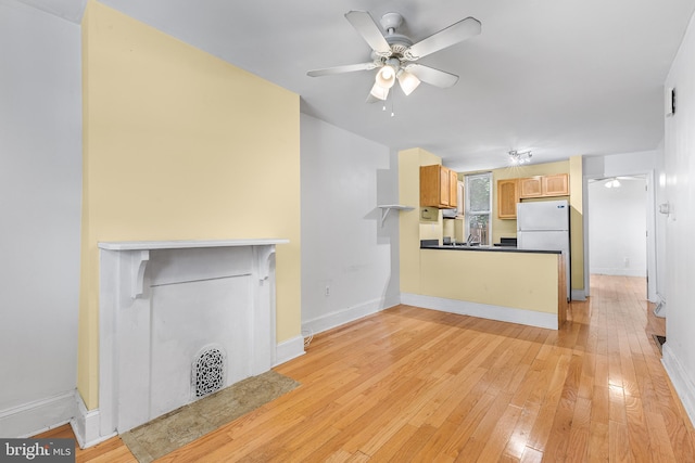 unfurnished living room featuring ceiling fan and light hardwood / wood-style flooring