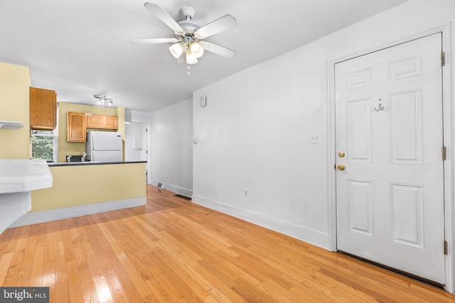 unfurnished living room featuring light wood-type flooring and ceiling fan