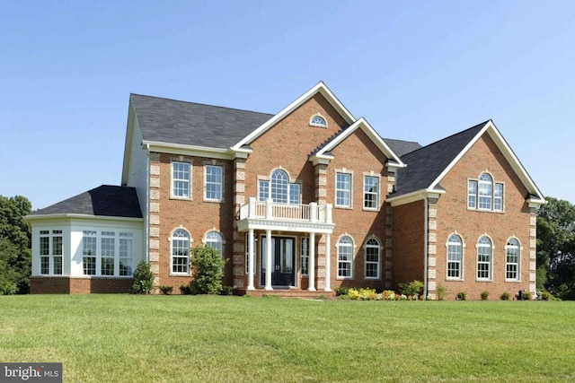 view of front facade with a balcony and a front yard