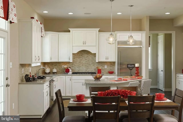 kitchen with sink, white cabinetry, hanging light fixtures, stainless steel appliances, and light stone counters