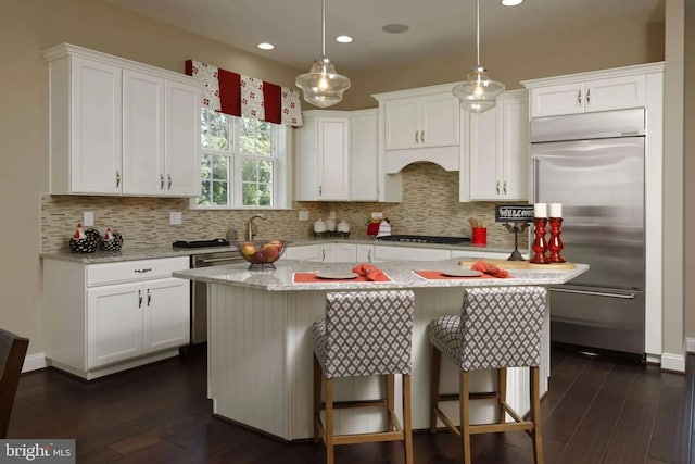 kitchen featuring a kitchen island, pendant lighting, white cabinets, and stainless steel built in fridge