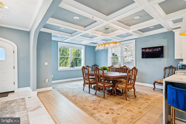 dining area with ornamental molding, light hardwood / wood-style floors, coffered ceiling, and beamed ceiling