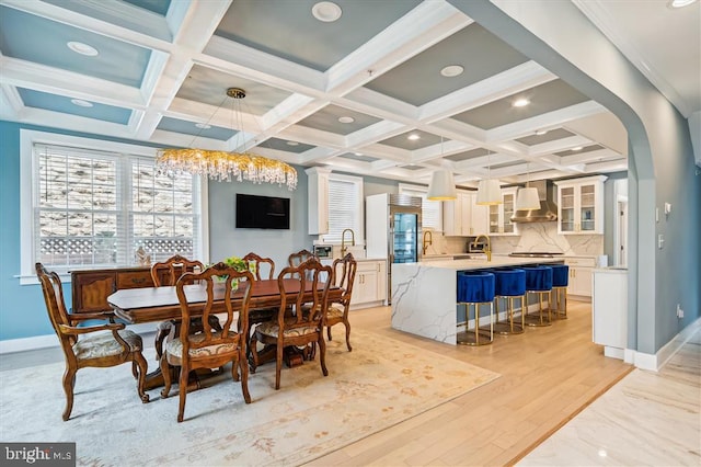 dining room featuring beam ceiling, coffered ceiling, and light hardwood / wood-style flooring