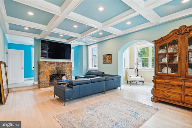 living room featuring beamed ceiling, a stone fireplace, and coffered ceiling