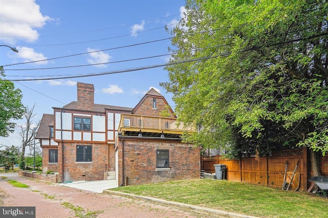 rear view of property featuring a balcony and a lawn