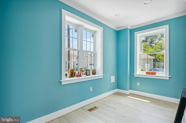 unfurnished room featuring ornamental molding and light hardwood / wood-style flooring