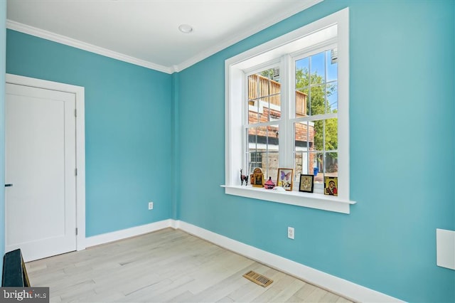 spare room with light wood-type flooring and crown molding