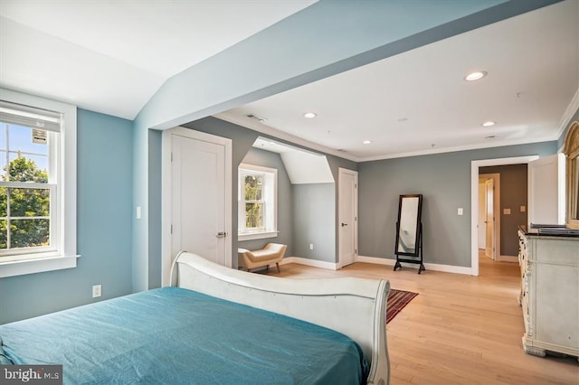 bedroom with vaulted ceiling, crown molding, and light hardwood / wood-style floors