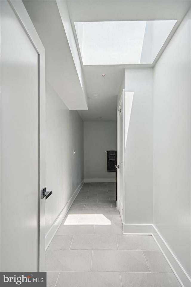 corridor with light tile patterned floors and a skylight