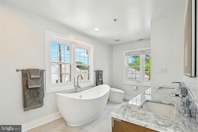 bathroom with plenty of natural light, tile patterned floors, a tub to relax in, and vanity