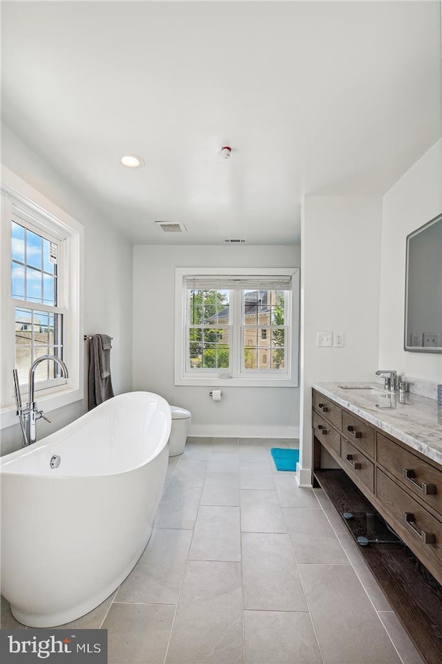 bathroom with a tub to relax in, vanity, and tile patterned flooring