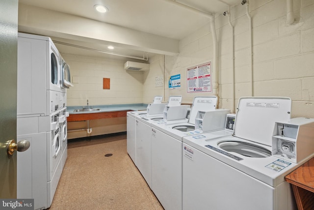 clothes washing area with sink, washer and clothes dryer, a wall unit AC, and stacked washer / dryer