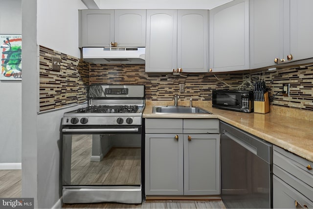 kitchen featuring appliances with stainless steel finishes, gray cabinets, sink, and decorative backsplash