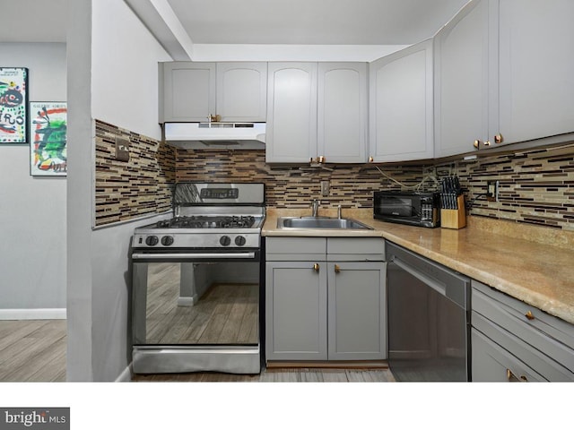 kitchen featuring gray cabinets, tasteful backsplash, sink, light hardwood / wood-style floors, and stainless steel appliances