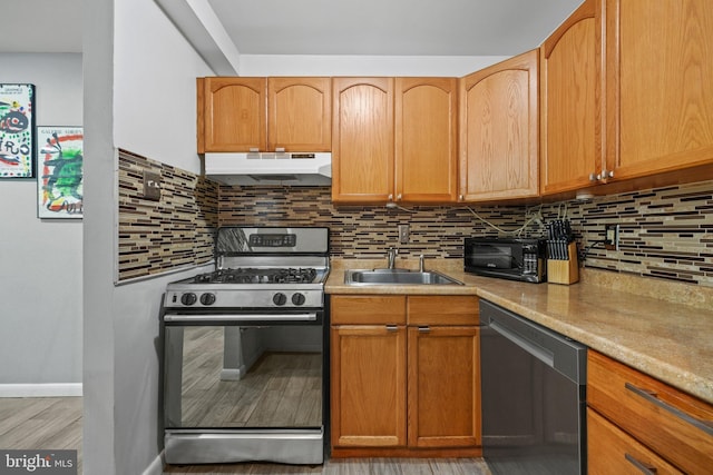 kitchen with sink, decorative backsplash, black appliances, and light stone countertops