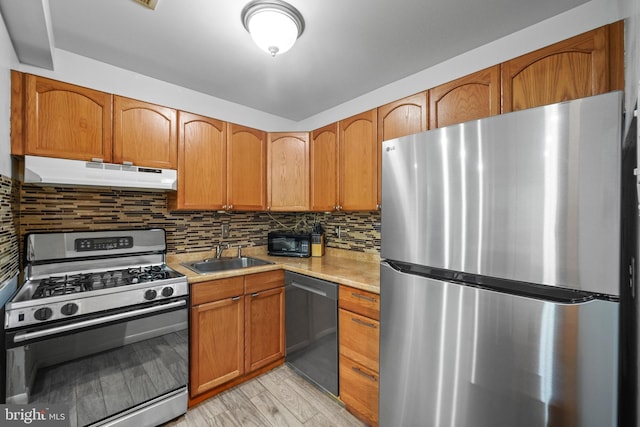 kitchen featuring sink, backsplash, light hardwood / wood-style floors, and appliances with stainless steel finishes