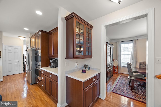 345 Austin Dr, Oxford, PA 19363 - kitchen featuring glass insert cabinets, light countertops, appliances with stainless steel finishes, crown molding, and light wood finished floors