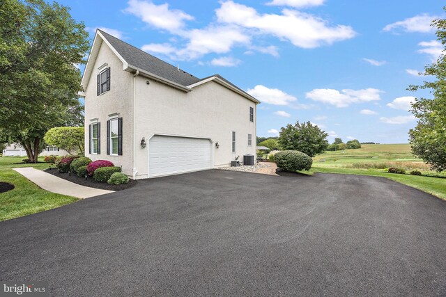 345 Austin Dr, Oxford, PA 19363 - view of side of home with central air condition unit, a garage, stucco siding, and aphalt driveway