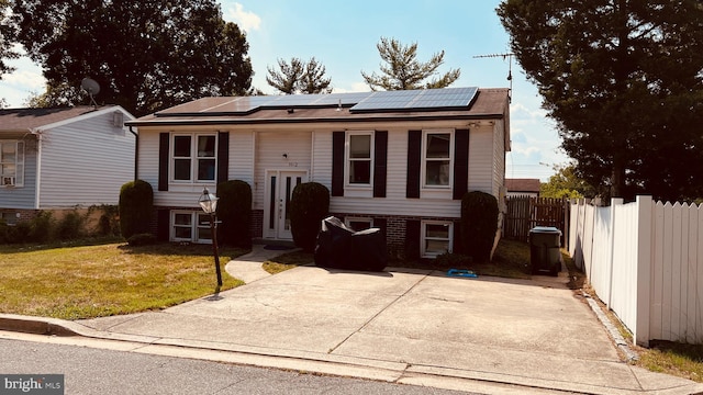 raised ranch featuring a front lawn and solar panels