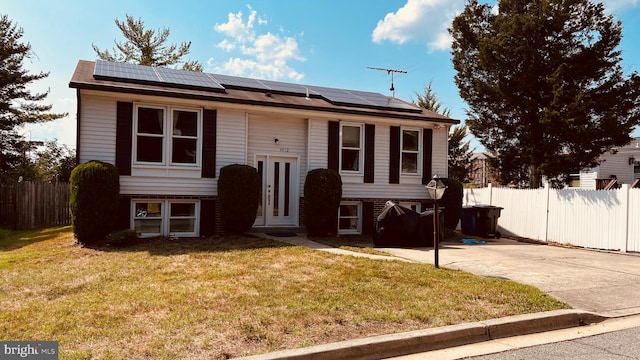 raised ranch featuring a front lawn and solar panels