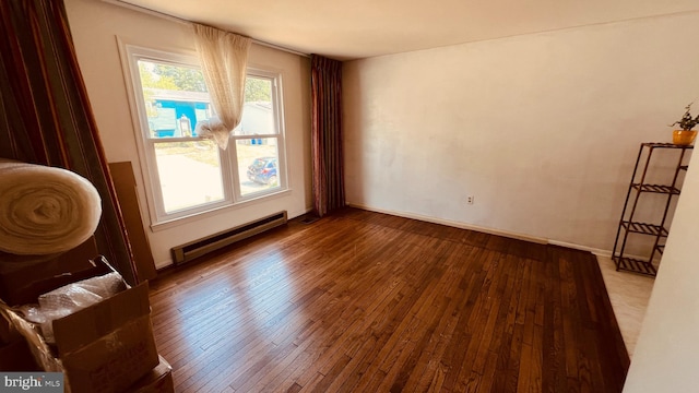 unfurnished room featuring baseboard heating and hardwood / wood-style floors