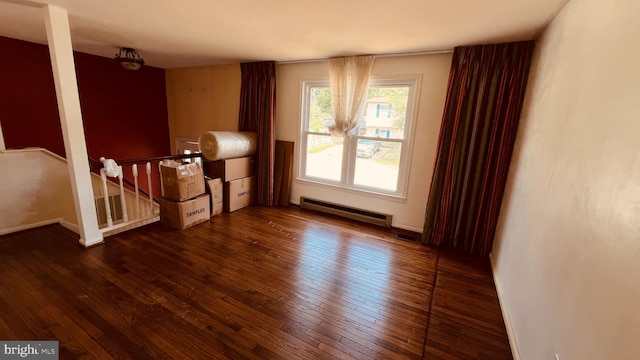 unfurnished room featuring baseboard heating and dark hardwood / wood-style flooring