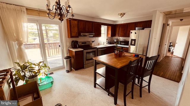 kitchen with sink, hanging light fixtures, light hardwood / wood-style flooring, an inviting chandelier, and appliances with stainless steel finishes