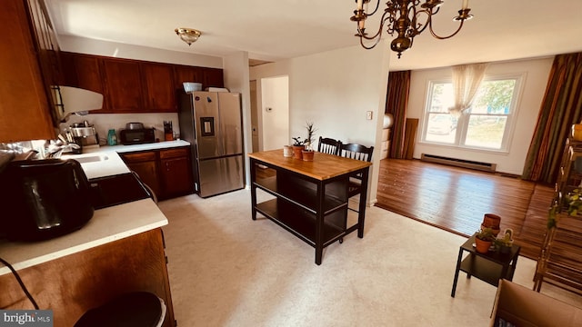 kitchen with light hardwood / wood-style floors, a notable chandelier, baseboard heating, decorative light fixtures, and stainless steel fridge