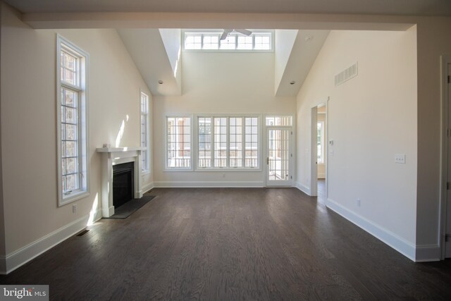 unfurnished living room with a towering ceiling, dark hardwood / wood-style flooring, and a wealth of natural light