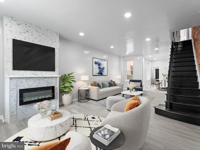 living room featuring light wood-type flooring and a stone fireplace