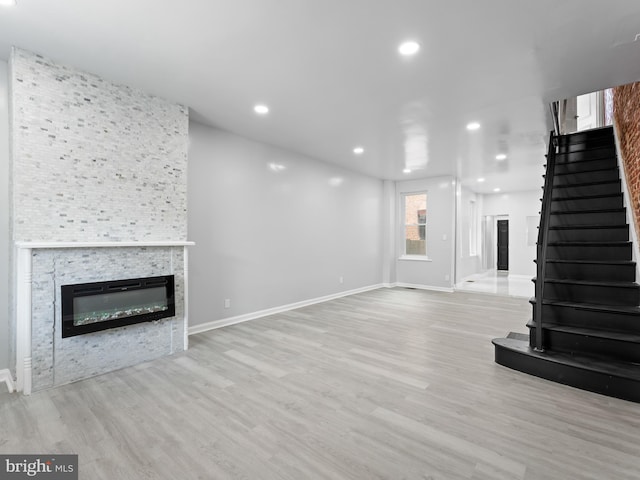 unfurnished living room featuring light hardwood / wood-style floors and a stone fireplace