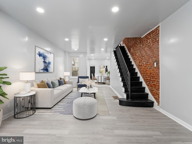 living room featuring brick wall and light wood-type flooring