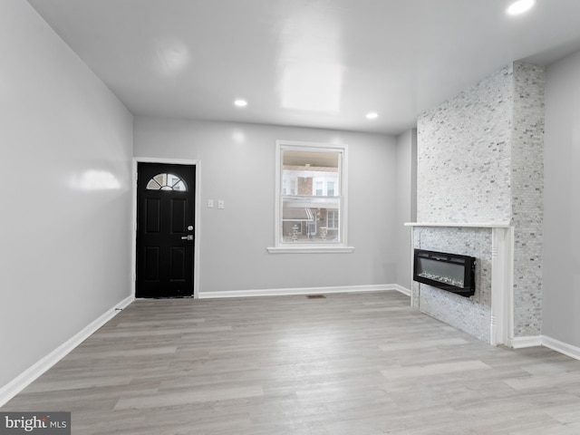 foyer entrance featuring light hardwood / wood-style flooring and a stone fireplace