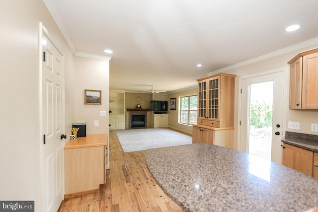 kitchen with stone counters, ceiling fan, crown molding, and light brown cabinets