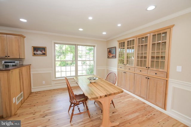 dining space with light hardwood / wood-style floors and ornamental molding