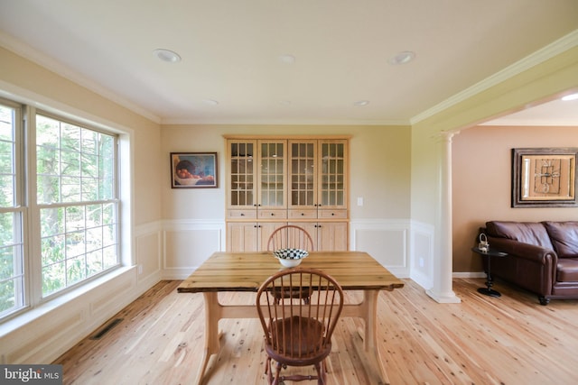 dining area featuring ornamental molding, a healthy amount of sunlight, light hardwood / wood-style flooring, and decorative columns