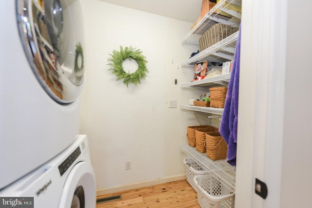 washroom with stacked washer / dryer and light hardwood / wood-style floors