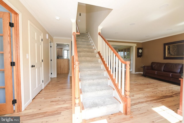 stairs featuring hardwood / wood-style floors and ornamental molding