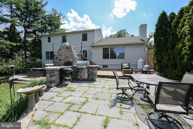 view of patio featuring a wooden deck, an outdoor stone fireplace, and area for grilling